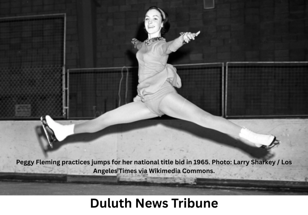 Peggy Fleming performing a mid-air split jump on an ice rink in 1965.